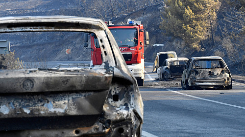 Hasičské vozidlo projíždí mezi vyhořelými auty po lesním požáru na pobřežní...