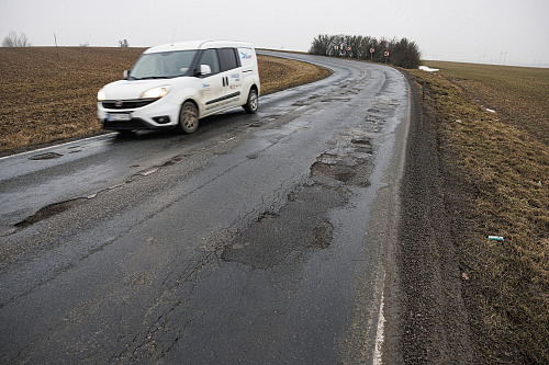 Silnice plná výtluků nedaleko Ostrovačic na Brněnsku u dálnice D1. (únor 2026)