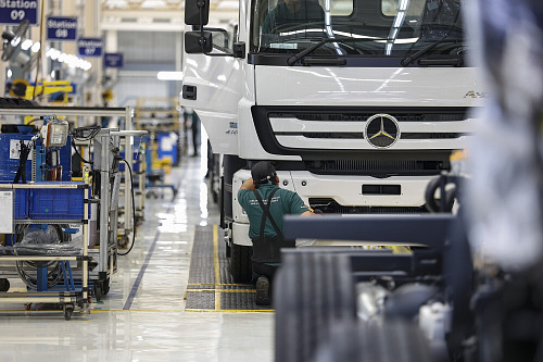 Pracovník montuje součásti nákladních vozidel Mercedes-Benz v továrně Daimler...