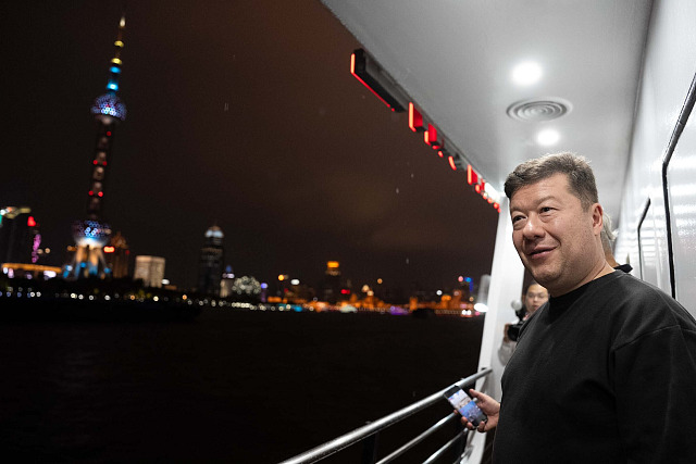 Tomio Okamura si během návštěvy Číny prohlíží noční Šanghaj z paluby lodi.