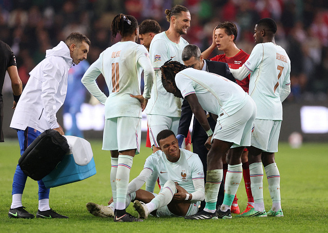 Kylian Mbappé si v hloučku svých francouzských spoluhráčů ohmatává zraněné...